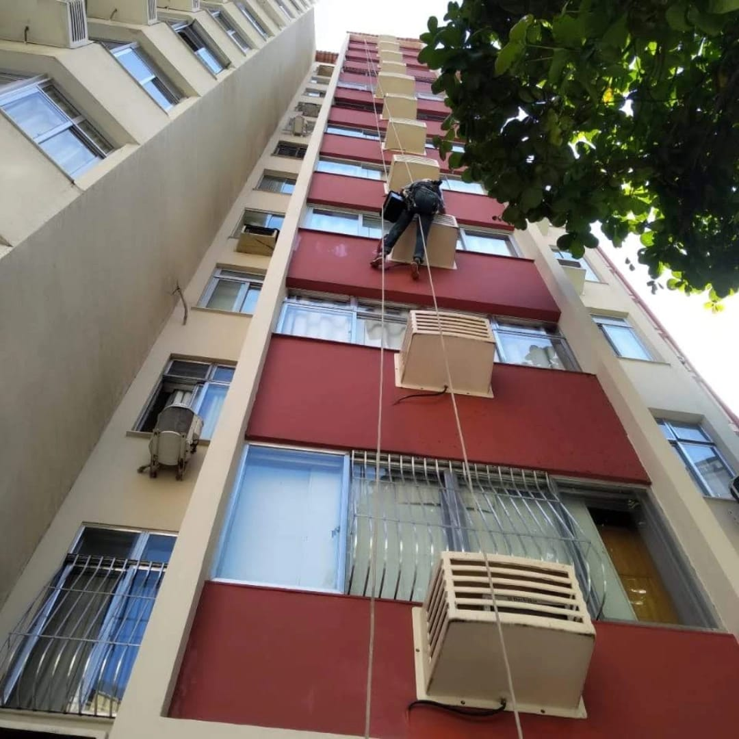 Profissional executando pintura em fachada predial